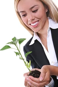 A business woman holding a small green plant
